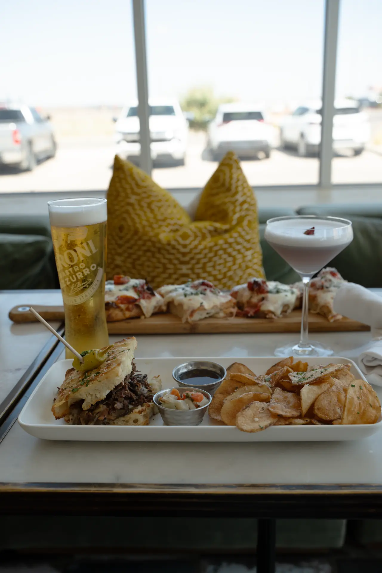 Table spread with sandwich, chips, and drinks at Candle Bar